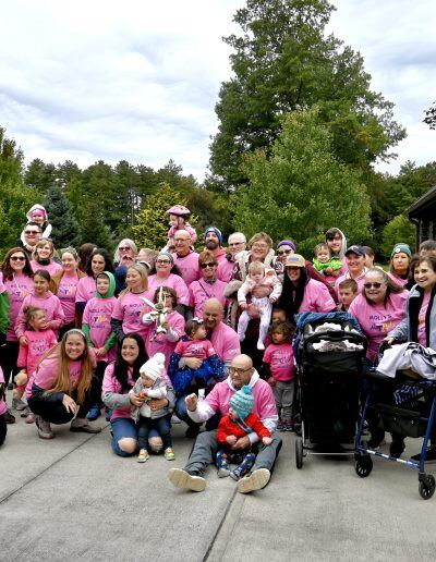 A large group of people pose for a photo together. Most people in in the photo are wearing pink shirts.