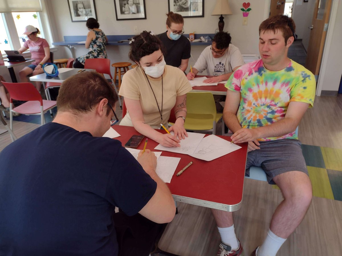 A group of people with light skin tones work on creating a comic book in class.